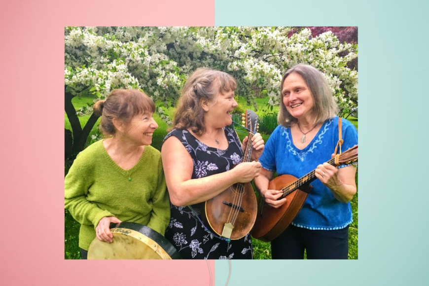 Three women standing in front of blooming apple trees holding instruments